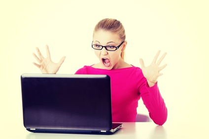 Young surprised woman sitting in front of laptop.